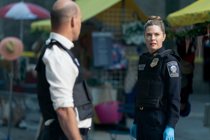 Officer speaks with plainclothes colleague by yellow tents