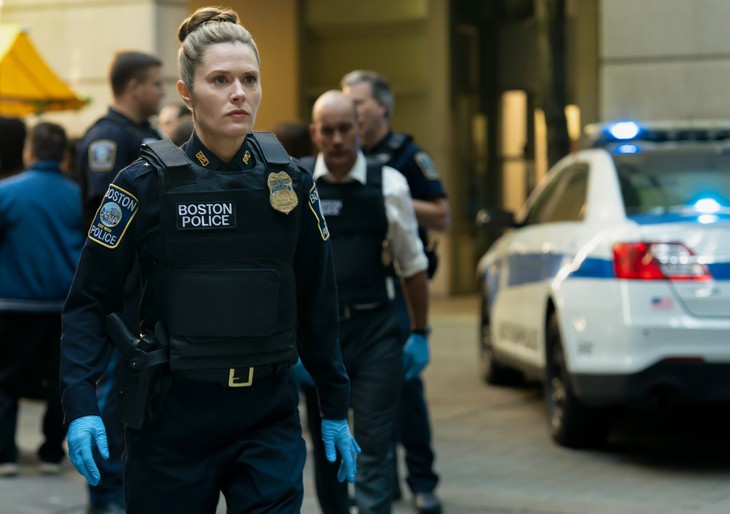 Officer striding through an active scene near patrol cars