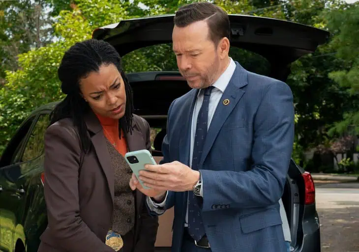 Investigators reviewing information on a phone beside their vehicle