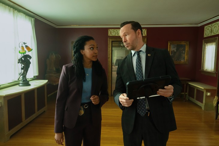 Investigators reviewing a tablet in a museum-like room